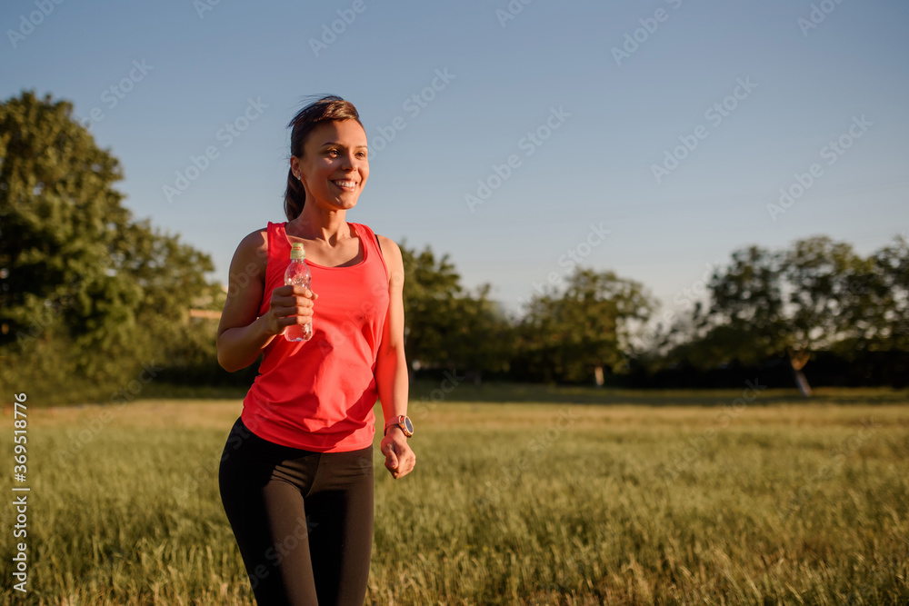 Young beautiful woman is making sport, she is running on a grass in the midst of nature on sunset. Young beautiful woman is making sport, she is running on a grass in the midst of nature on sunset.