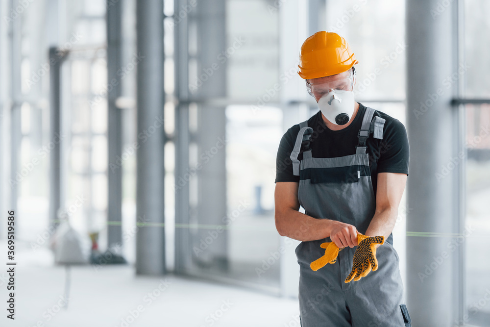 Man in grey uniform preparing for work indoors in modern big office at daytime Man in grey uniform preparing for work indoors in modern big office at daytime