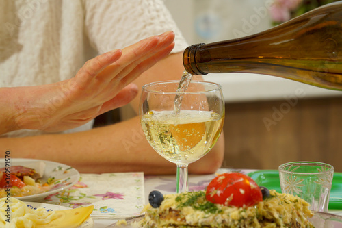 The hand of a young woman gestures that she has enough wine. photo