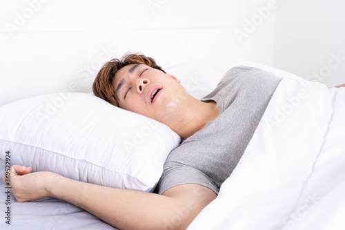 Obraz na plátně Man snoring loudly because of tired from work, sleep apnea lying in the bed