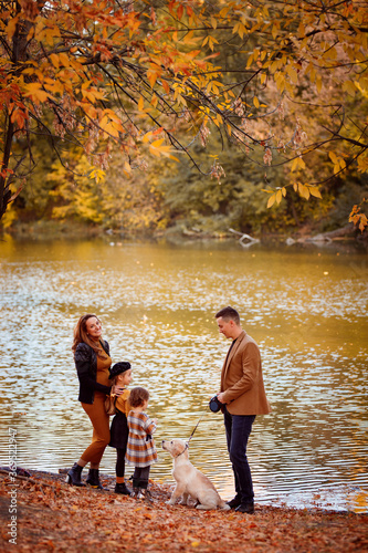 family with dog walking in autumn Park by river.