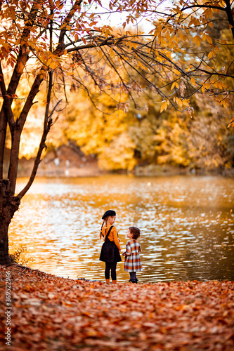 little girls standing on river bank in autumn park