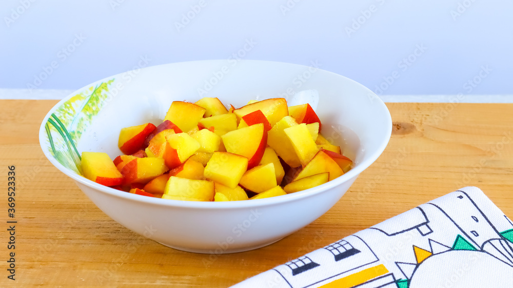Bright yellow fruit sliced peach in a plate on a wooden surface Bright yellow fruit sliced peach in a plate on a wooden surface