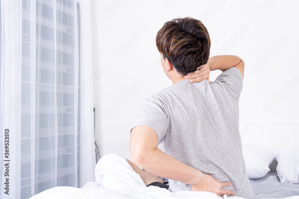 Young man suffering neck and back pain from uncomfortable bed. Healthcare medical or daily life concept. Young man suffering neck and back pain from uncomfortable bed. Healthcare medical or daily life concept.