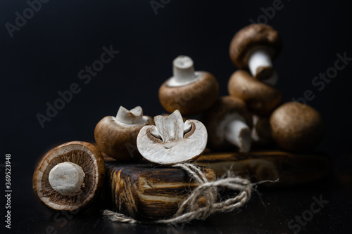 Fresh white champignons on the dark kitchen table. Cooking delicious dishes with mushrooms