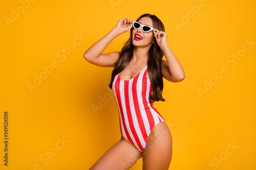 Photo of beautiful lady toothy smile slim figure bronze body seashore life guard control use sun specs glasses wear white red striped bodysuit isolated bright yellow color background