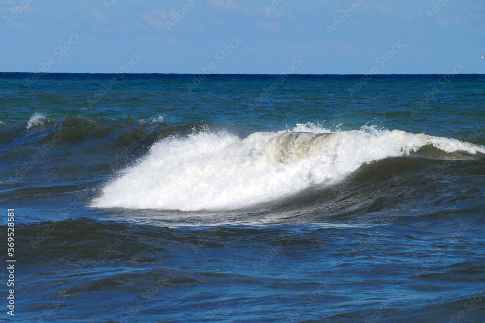 big foamy wave at sea on a sunny day