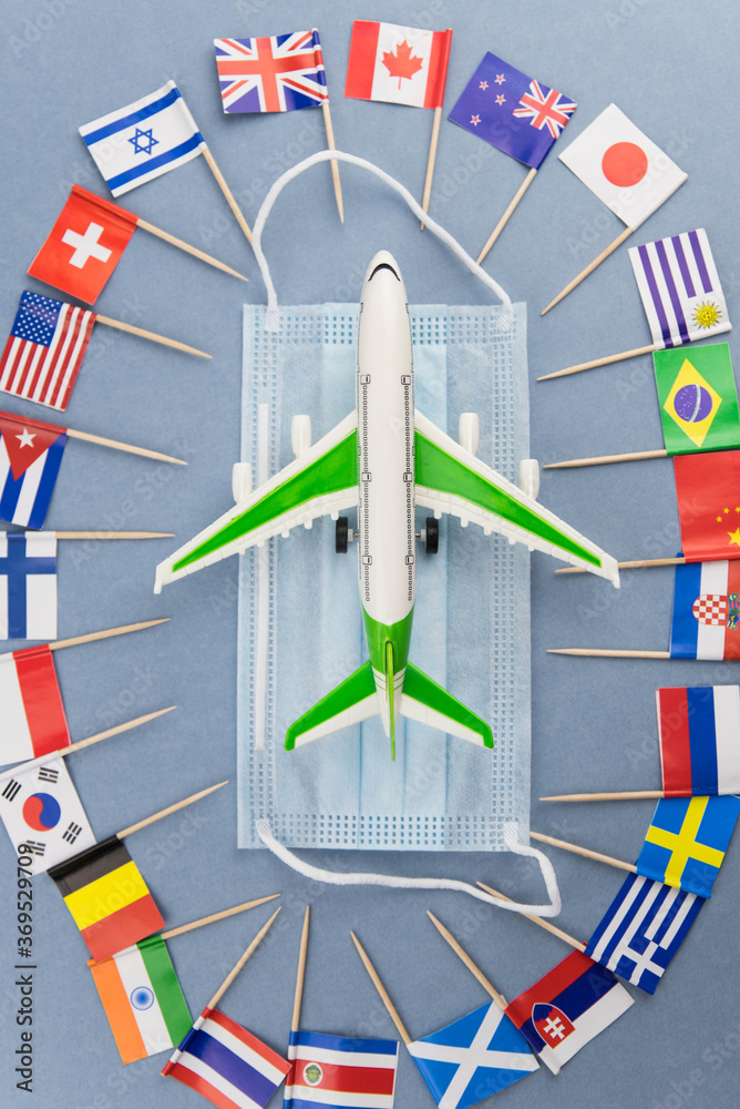 Safe travels concept. Plane with surgical medical mask. Safety flight and travel during quarantine and lockdown. Passenger airplane on national flag background. Flight permit.