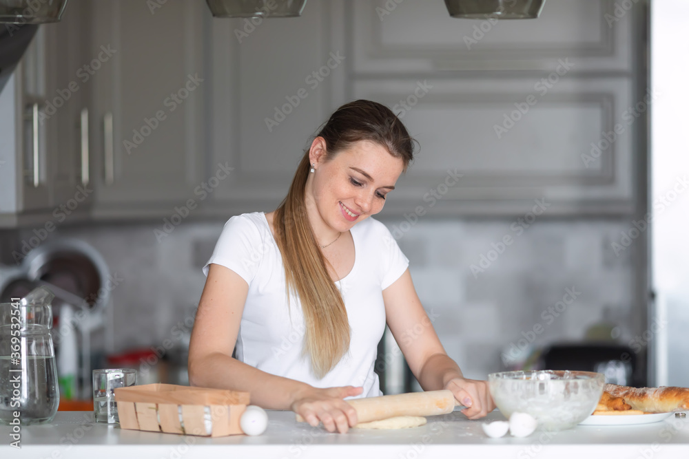 Young woman knead dough at kitchen.Female confectioner preparing pie, cookies or cake at home.