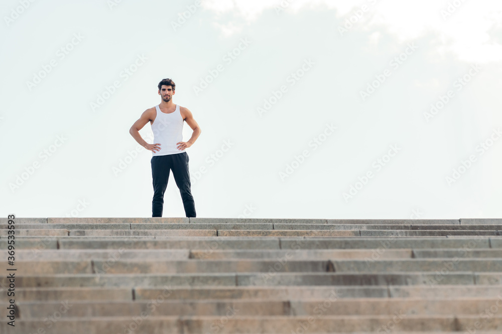sportsman with hands on hips at top of a staircase
