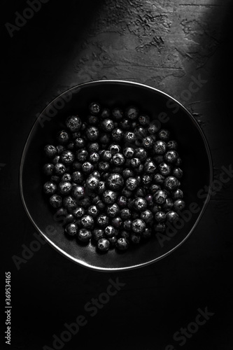 Bilberry in a black plate on black background, top view