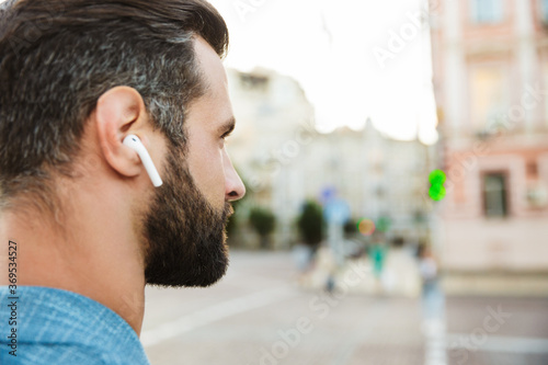 Confident young man wearing wireless earphones