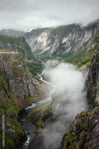 A gorge above a mountain river in Norway with a low floating cloud. View from above.
