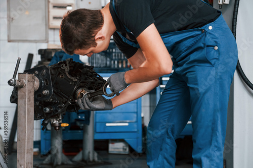 Professional repairman in garage works with broken automobile engine