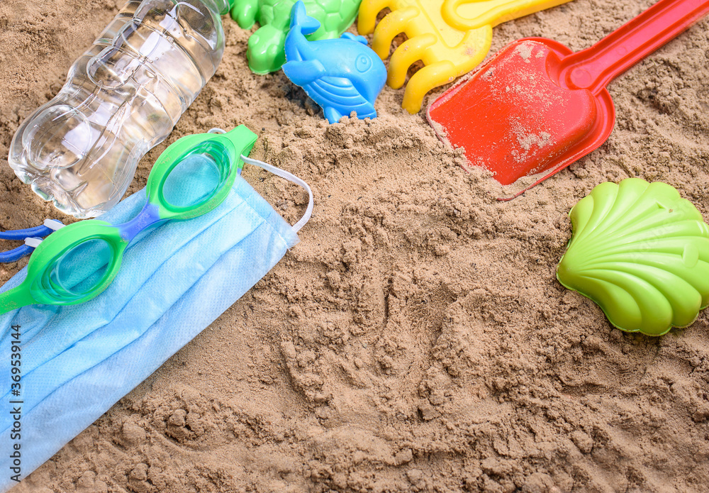 Beach sand with toys for the baby, water, the word summer in colored letters. Staycation content Beach sand with toys for the baby, water, the word summer in colored letters. Staycation content