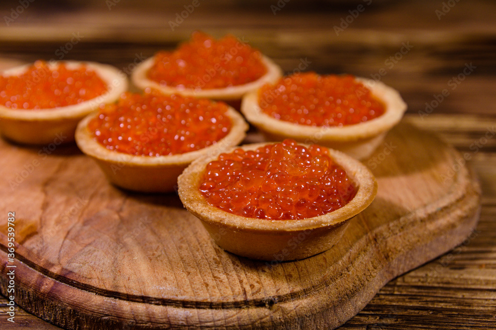 Tartlets with red caviar on a wooden cutting board. Festive food Tartlets with red caviar on a wooden cutting board. Festive food
