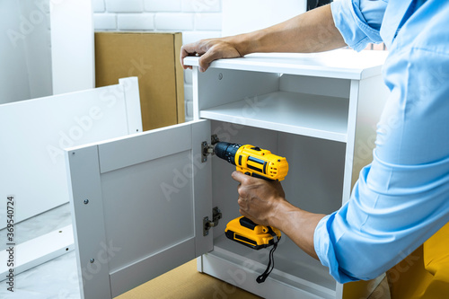 Slika na platnu Man doing renovation work at home drilling wood with drill tack on locker