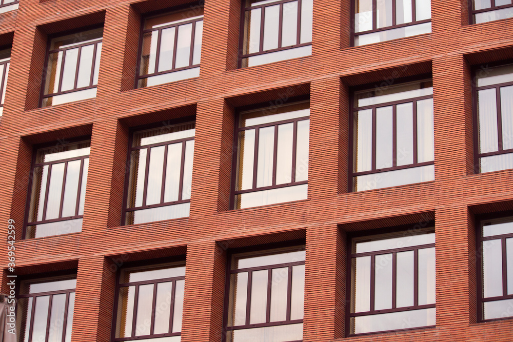 Urban texture and pattern. Architecture. Closeup view of the building facade. The apartment windows and the red brick wall.
