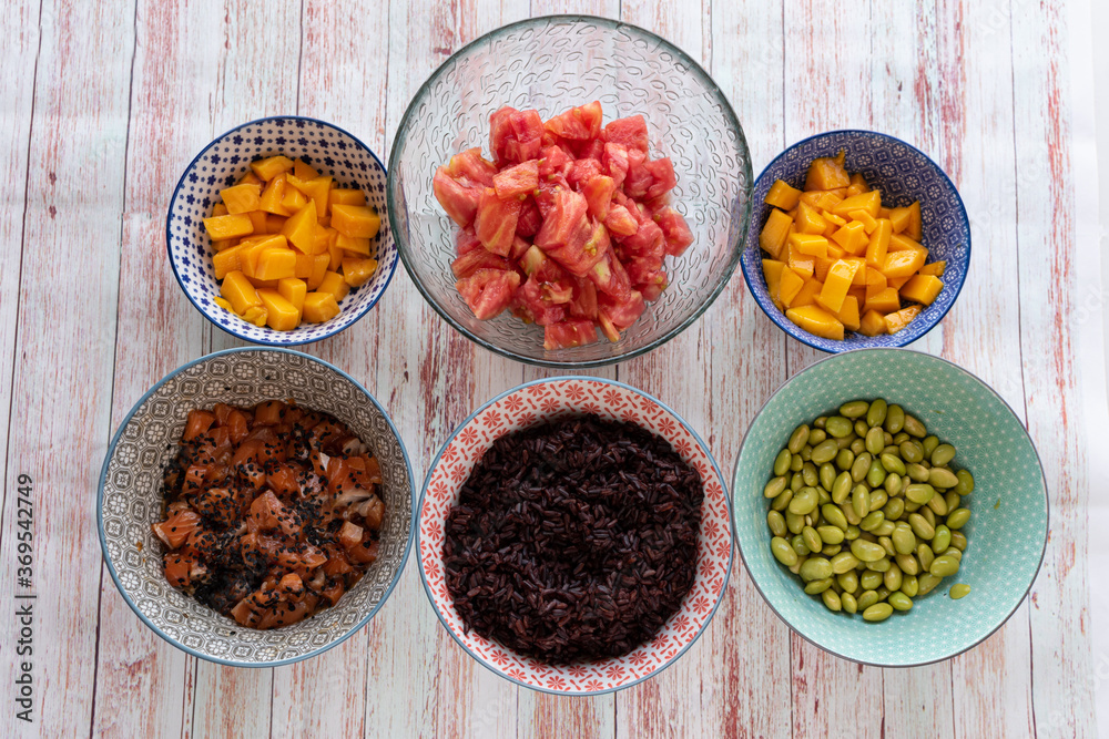 ingredients for a poke in a bowl. Tomatoes, black rice, tuna or salmon, mango and soybeans ingredients for a poke in a bowl. Tomatoes, black rice, tuna or salmon, mango and soybeans