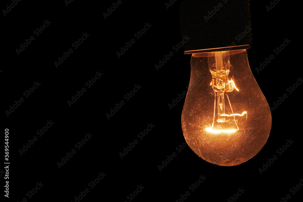 incandescent lamp burning yellow in the dark of night with place for text incandescent lamp burning yellow in the dark of night with place for text