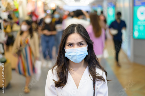 A woman is wearing protective mask on Street with Crowded people while covid-19 pandemic, Coronavirus protection , safety lifestyles concept