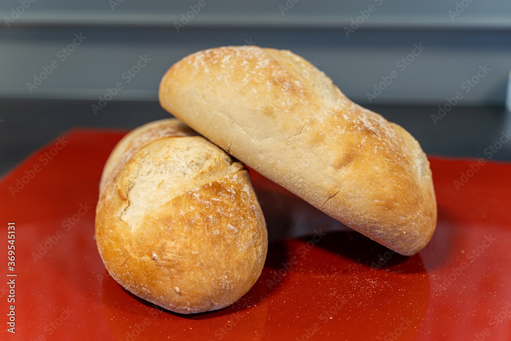 Two fresh breads with a golden crust lie on the red table