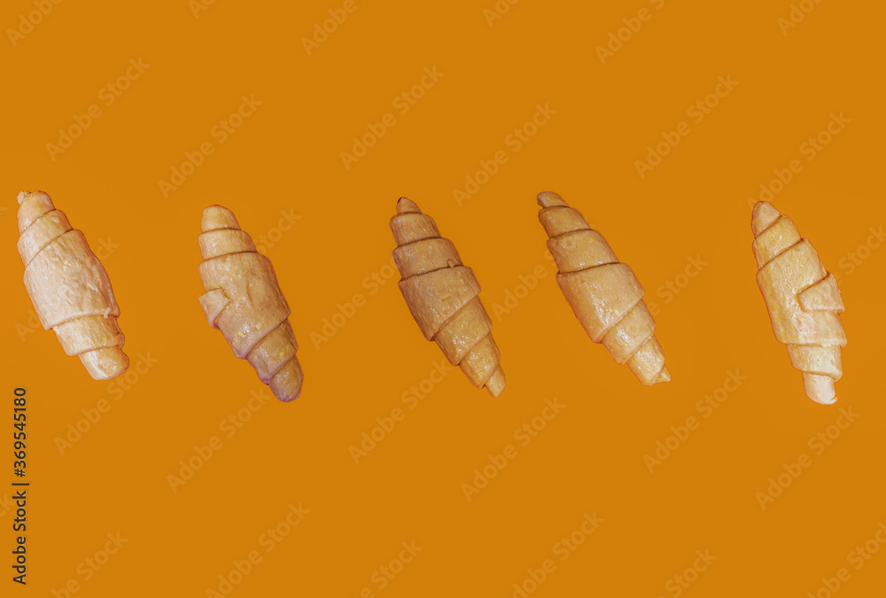 Golden croissants on an orange background. Place for text Golden croissants on an orange background. Place for text