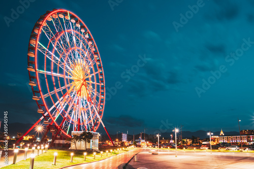 Batumi, Adjara, Georgia. Ferris Wheel At Promenade In Miracle Park, Amusement City Park On Blue Evening Sky Background. Evening Or Night Time