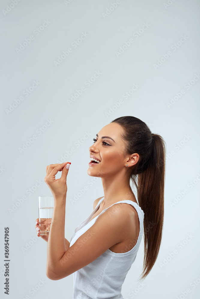 Happy Smiling Woman Taking Pill With Cod Liver Oil Omega-3 And Holding A Glass Of Fresh Water In Morning. Vitamin D, E, A Fish Oil Capsules. Diet. Nutrition. Healthy Eating Happy Smiling Woman Taking Pill With Cod Liver Oil Omega-3 And Holding A Glass Of Fresh Water In Morning. Vitamin D, E, A Fish Oil Capsules. Diet. Nutrition. Healthy Eating