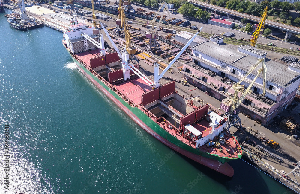 A cargo ship at the pier in the port. The loading process is in progress. View from above.