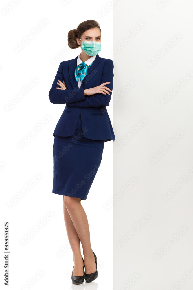 Stewardess Wearing Protective Face Mask Is Leaning On A White Wall Stewardess Wearing Protective Face Mask Is Leaning On A White Wall