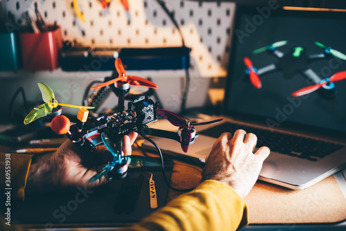 Man controlling FPV drone and using laptop.