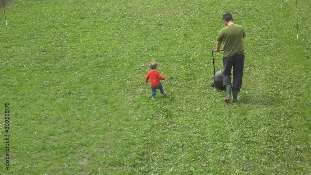 Father with lawn mower baby child running, up view Father with lawn mower baby child running, up view