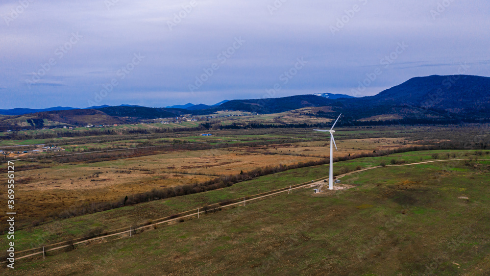 View of a wind turbine in the mountains in the background, Alternative energy, Ukrainian windmill in a field in the Carpathian region.