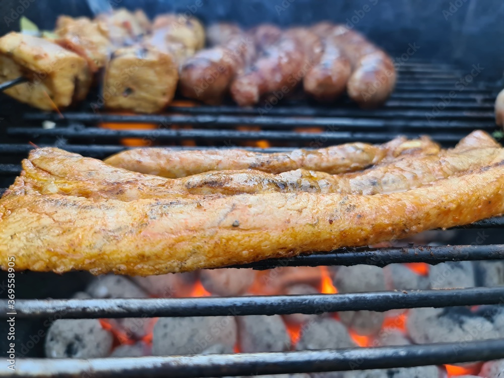 Bauchfleisch sowie Bratwurst und Fleischspieße auf einem Grill Stock ...