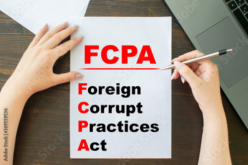 a girl writes an inscription on a sheet of paper Paper with words FCPA Foreign Corrupt Practices Act photo