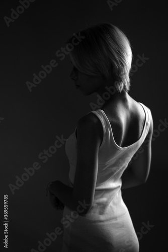  young sad woman looks away  a dark black and white photo. Stands sideways .