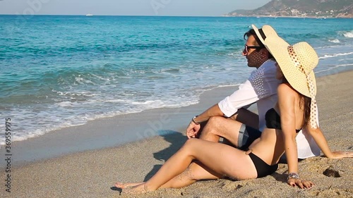 Young happy couple relaxing on tropical beach by sea. Summer vacation