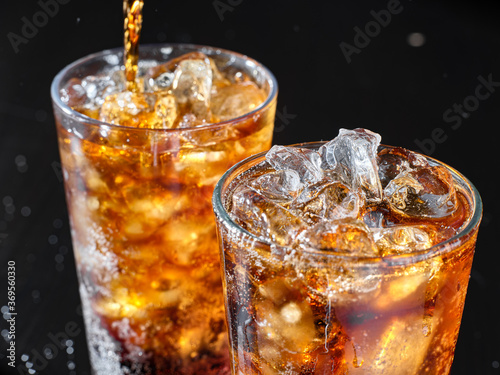 two cups of cola soft drink being poured into glass