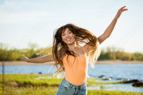 A cheerful woman jumps for joy in nature against the background of the bay