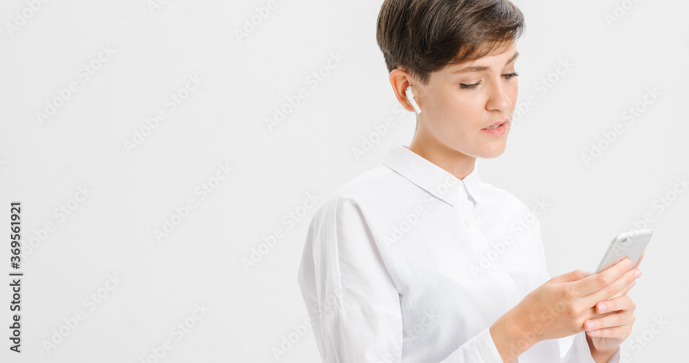 a young woman uses wireless headphones for a video call. white background in studio. online business meeting concept a young woman uses wireless headphones for a video call. white background in studio. online business meeting concept
