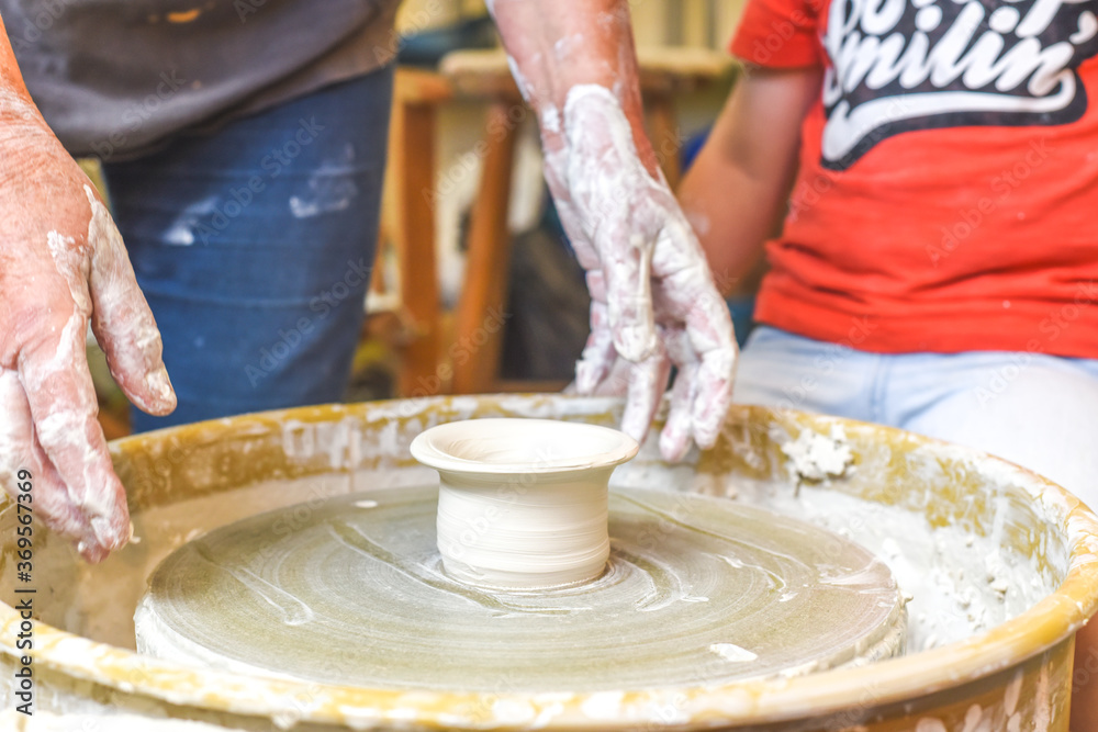 Children making pottery during ceramic lesson with clay