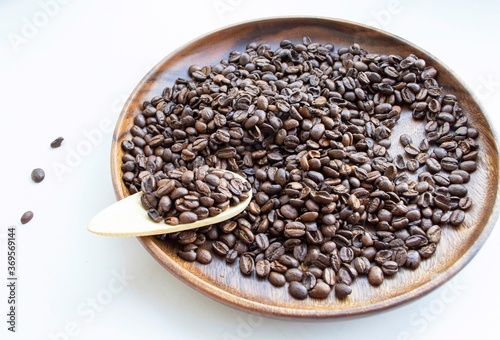 Coffee beans in a dish made of wood, on a light background