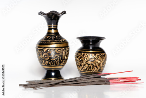 Antique etched brass vase and incense sticks isolated on white background