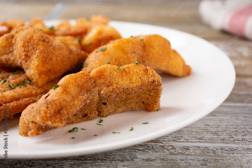 A view of a plate of deep fried catfish, in a restaurant or kitchen setting.