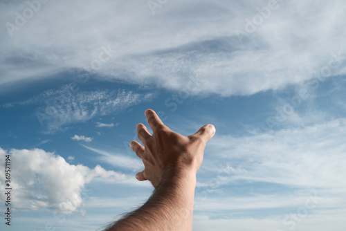 фотографія A hand reaching into the sky. Point of view. Sunlight.