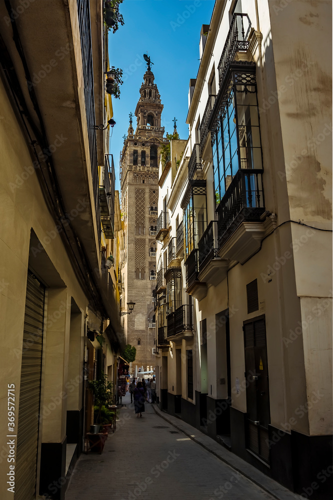 A glimpse down a street in Seville, Spain towards the tower of the cathedral of St Mary in the summertime