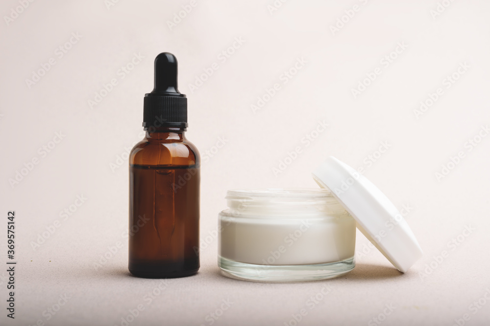Serum glass bottle with pipette and jar of facial or body cream. Serum glass bottle with pipette and jar of facial or body cream.