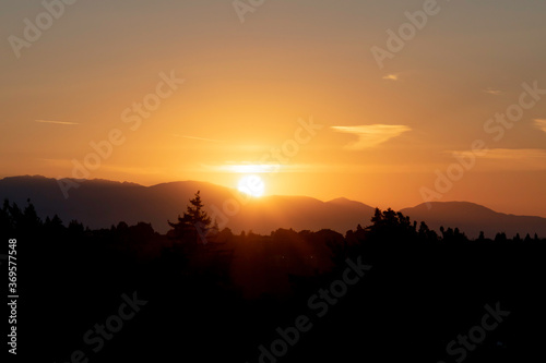 The sun sets behind the Olympic Mountains in Washington State. The view of the Olympic mountain range is from the Capitol Hill district in Seattle.