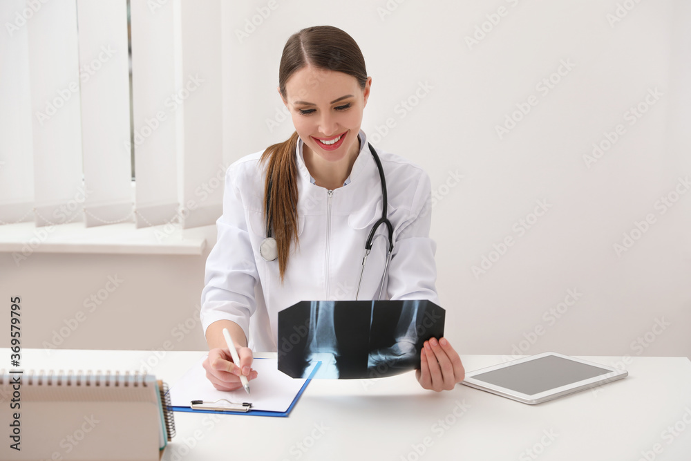 Orthopedist examining X-ray picture at desk in clinic Orthopedist examining X-ray picture at desk in clinic